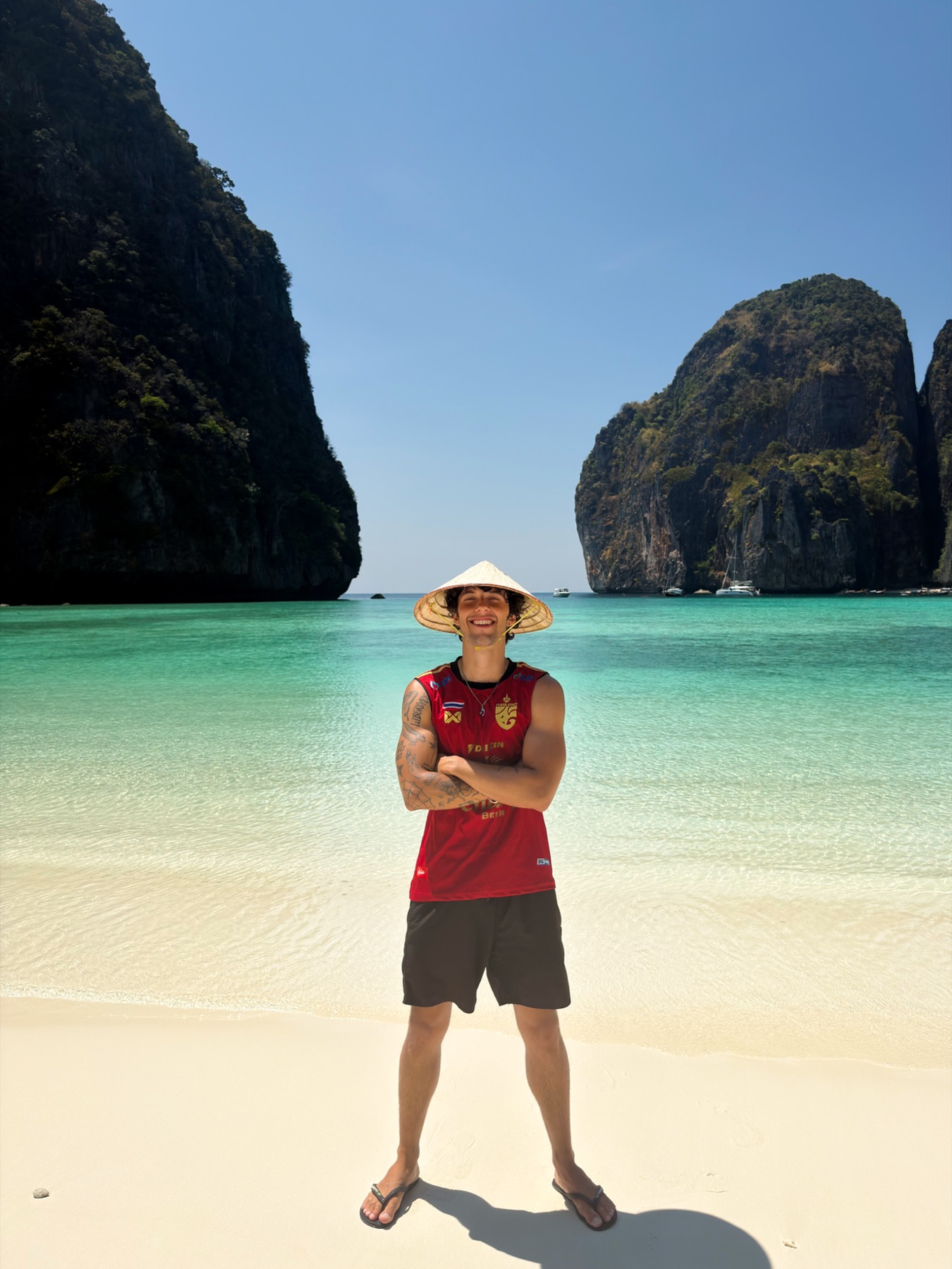Verly sorrindo, de chapéu, em uma praia da Tailândia.